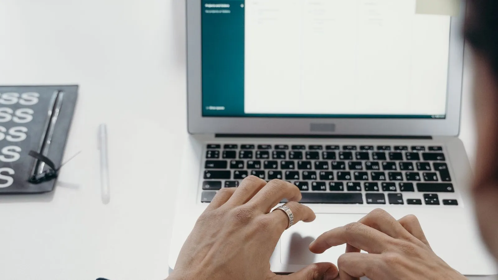 Person typing on a laptop in a bright office