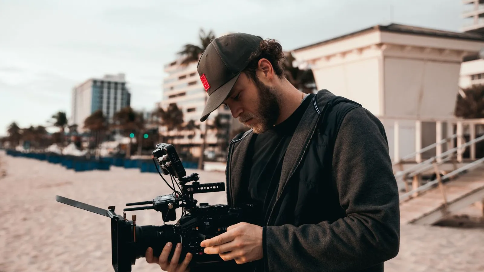 Videographer checking a cinema camera on a sunny beach (illustration photo)
