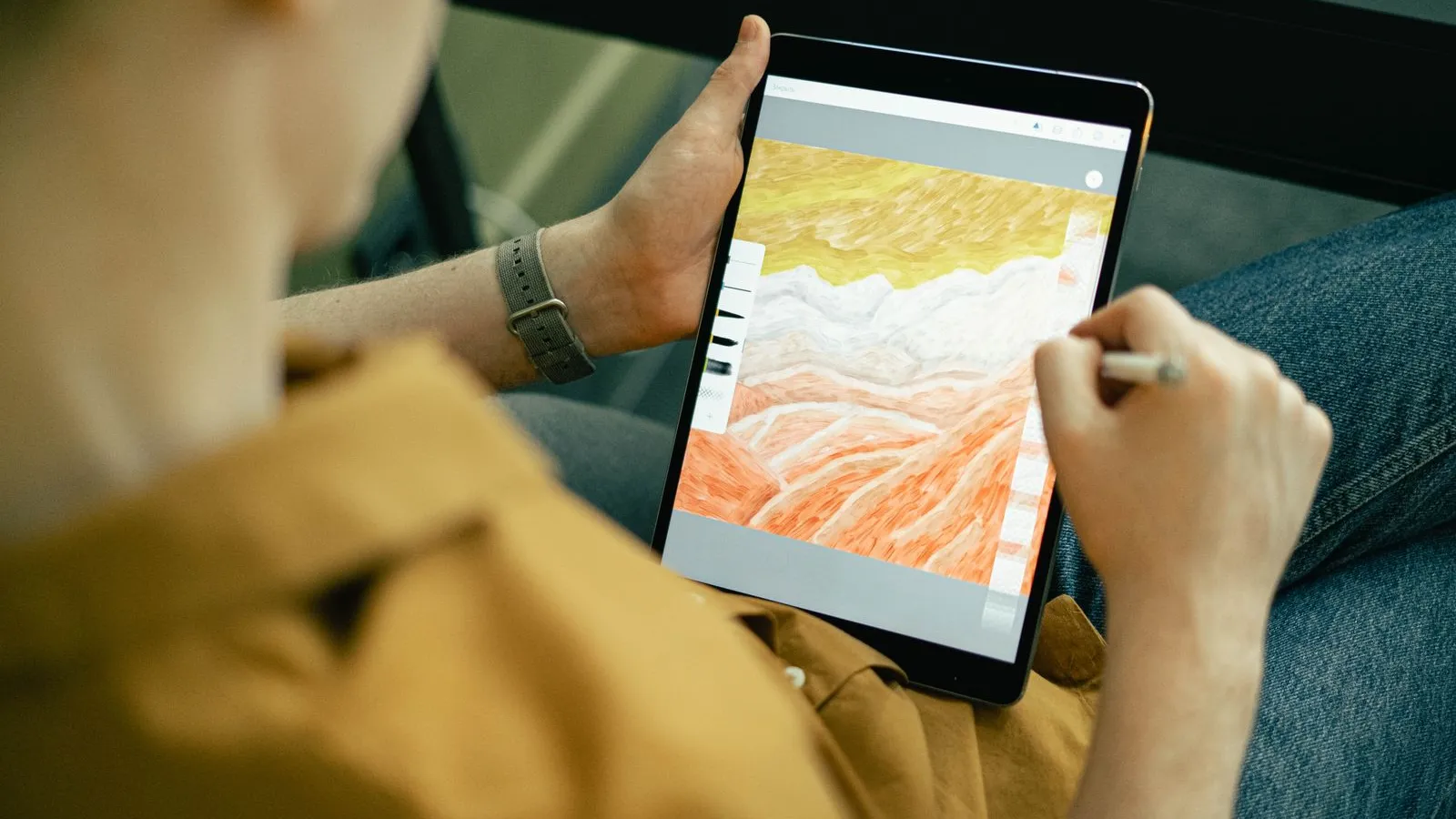 Person drawing a colourful landscape on a tablet with a stylus