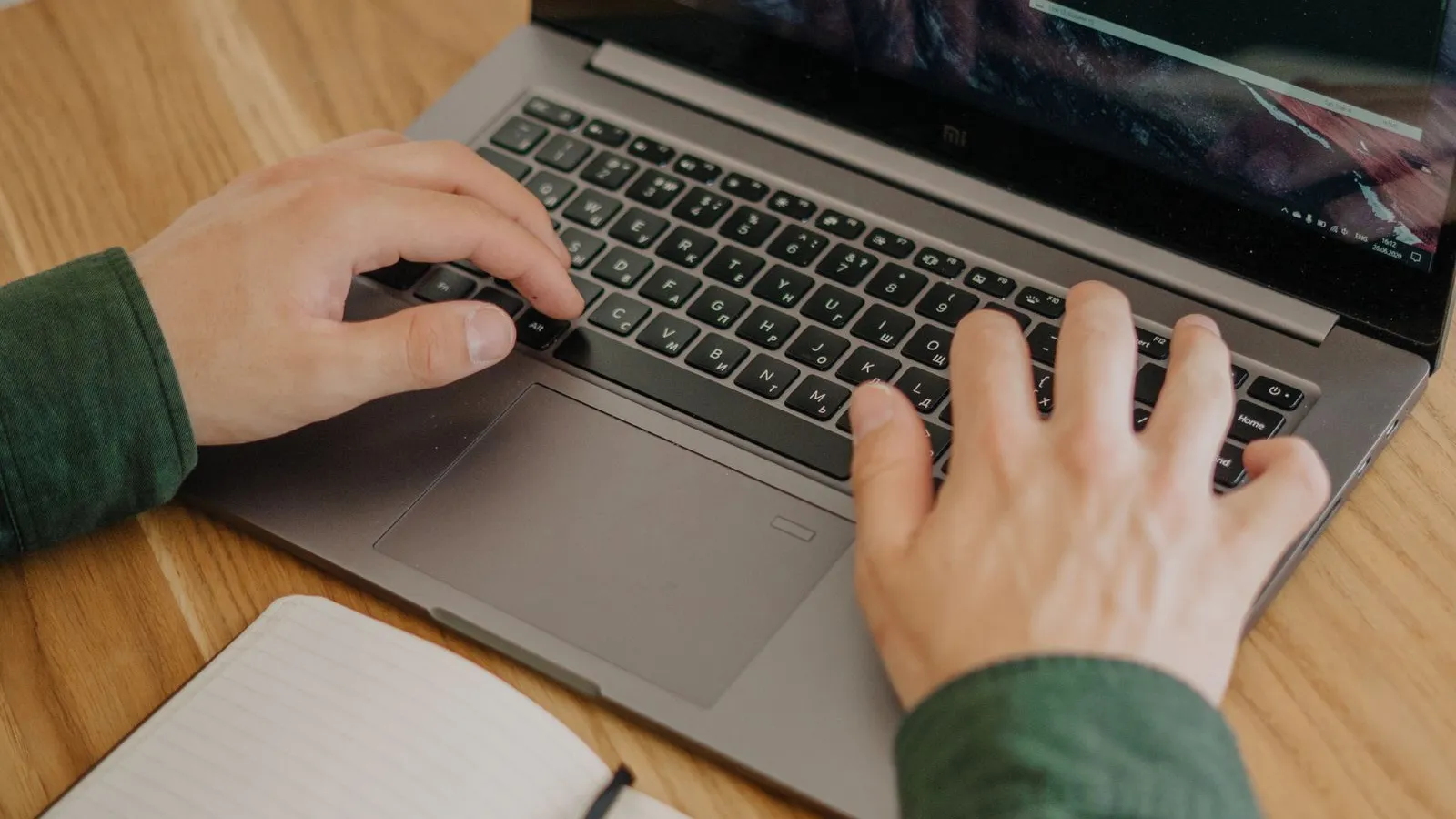 Person working on a laptop with a terminal open on a wooden desk